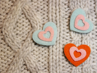 Fototapeta na wymiar Hearts made of felt on knitted background