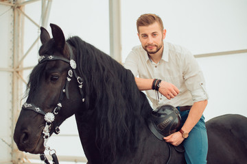 Handsome man in a shirt riding on a brown horse