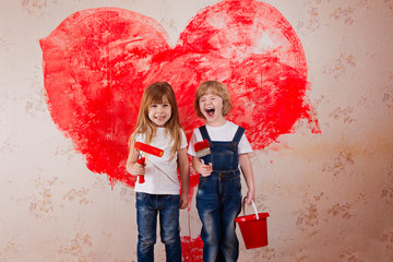 a boy and a girl with a roller in jeans and a white T-shirt, a brush and a bucket paint the wall in red.