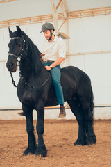 Handsome man in a shirt riding on a brown horse