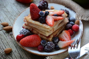 Thin pancakes with jam and berries