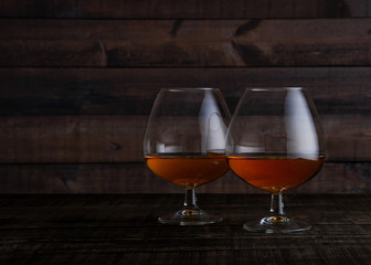 Glasses of brandy cognac shot on wooden table