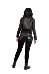 Fototapeta premium full length portrait of black haired girl wearing leather outfit. standing pose view from behind, on a white background