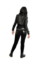 Fototapeta premium full length portrait of black haired girl wearing leather outfit. standing pose view from behind, on a white background