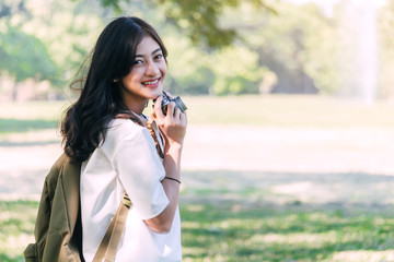 Asian woman taking picture with camera in park