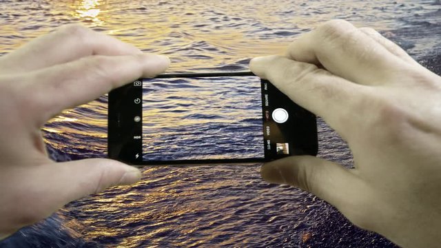 Cell phone in hand taking video of Cape Cod beach