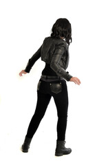 Fototapeta premium full length portrait of black haired girl wearing leather outfit. standing pose view from behind, on a white background