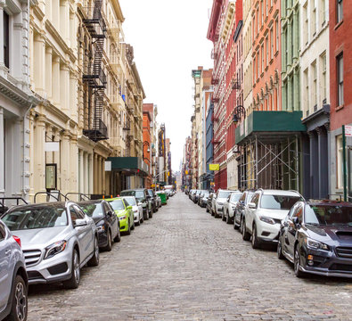 New York City cobblestone street scene with buildings and cars in the historic SoHo neighborhood of Manhattan