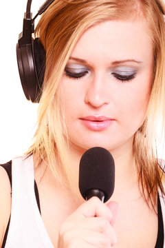 Woman singing to microphone wearing headphones