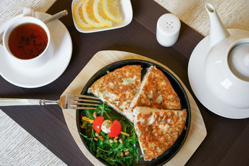 A healthy breakfast, scrambled eggs, tea, cheese, butter, fresh herbs. Top view, close-up. Healthy food.