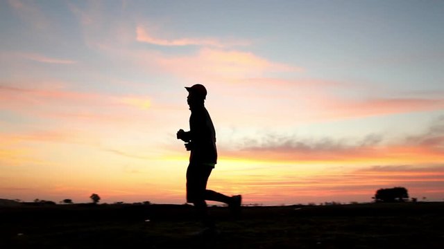 Athletic man running with sunset or sunrise background,moving shot by slider