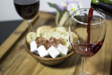 Red wine in a glass and a set of products -cheese, salami, and bread