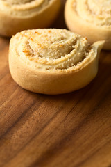 Freshly baked sweet coconut rolls on wooden plate, photographed with natural light (Selective Focus, Focus in the middle of the first roll)
