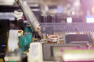 Soldering to a circuit Board of a computer close up.