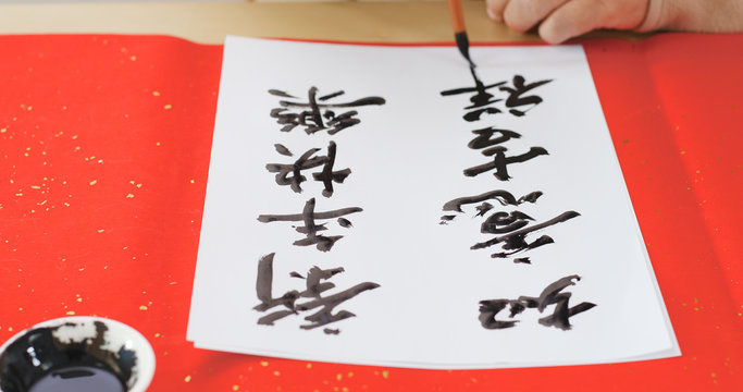 Writing Chinese calligraphy with phrase meaning wish you good fortune and may all your wishes come true