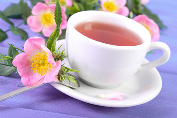 Cup of tea and wild rose flower on boards