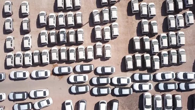 New cars covered in protective white sheets parked in a holding platform - Aerial footage