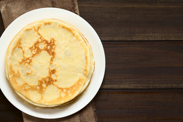 Hausgemachte frische Crepe oder Pfannkuchen auf Teller gestapelt, fotografiert mit natürlichem Licht (Selektiver Fokus, Fokus auf den oberen Crepe)