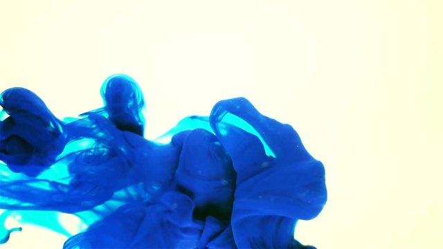  Macro shot of blue ink dropped into water, slow motion on white background 