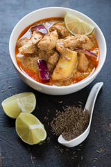 White bowl with chicken massaman curry over dark brown stone background, studio shot