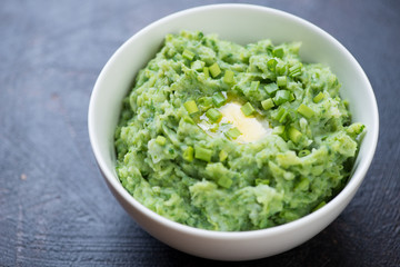White bowl with Irish colcannon or mashed potato with kale, leek and green onion, traditional meal for Saint Patrick’s Day, close-up