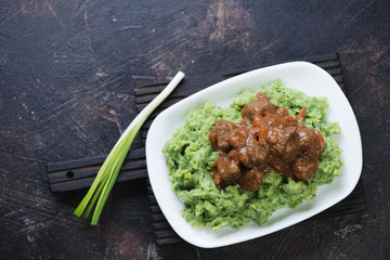 Irish traditional colcannon with beef and beer stew, view from above on a dark brown stone background with space, studio shot