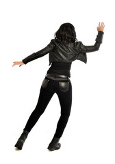 full length portrait of black haired girl wearing leather outfit. standing pose  view from behind, on a white background