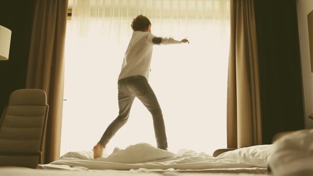 Cheerful fashion dressed boy active jumping on the bed in the morning