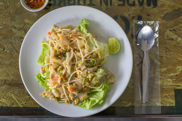 Stir Fried Noodles with Chicken with vegetable and fish sauce on the wooden Table, Thai food