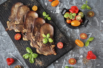 Grilled beef tongue, fresh pepper, chili, Basil on grey stone background