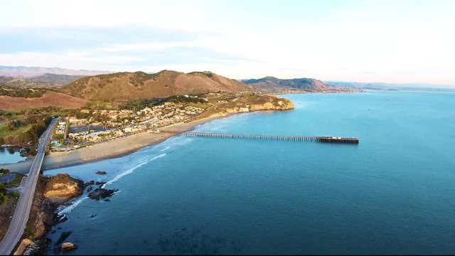 Aerial Flyover - Avila Beach seaside town drone ascending view with a pier and mountains