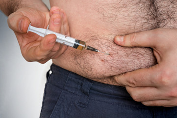 Diabetic man with syringe inject insulin to his belly