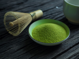close up green tea, matcha power and whisk a cup of hot green tea on wooden table.traditional...
