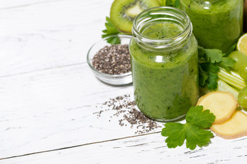 green fruit and vegetable smoothies in jars on white table, top view