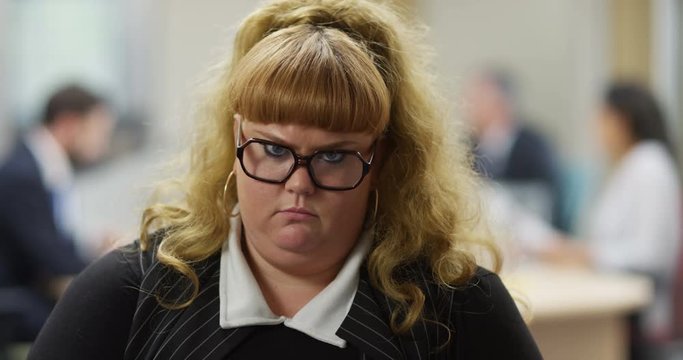 4K Portrait grumpy overweight businesswoman frowning at camera. Slow motion.