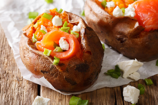 Healthy food: sweet potato stuffed with salmon, feta cheese and green onions close-up on parchment