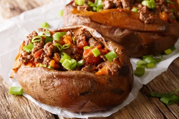 Poster Organic food: baked sweet potato stuffed with ground beef and green onion close-up on paper. horizontal © FomaA