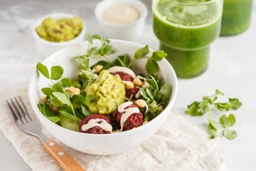 Green vegetable vegan salad with beets meatballs, Guacamole, tahini dressing and green juice. Healthy vegetarian food concept.