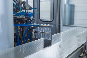 Plastic water bottles on conveyor and water bottling machine industry.