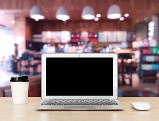 Laptop Computer on a wooden desk with coffee shop blurry background