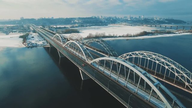 Cars and train moves on a bridge over a frozen river aerial drone footage