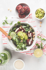 Vegan lunch flat lay. Green vegetable vegan salad with beets meatballs, Guacamole and tahini dressing. Healthy vegetarian food concept. Copy space, top view