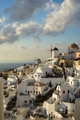 Beautiful evening light scene of Oia white building townscape and windmill along island mountain, Aegean sea, abstract cloud and blue sky background