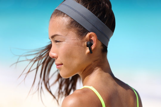 Wireless earbuds woman listening to music on beach