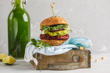 Vegan beet burger with vegetables, guacamole and rye bun with green juice. Healthy vegan food...