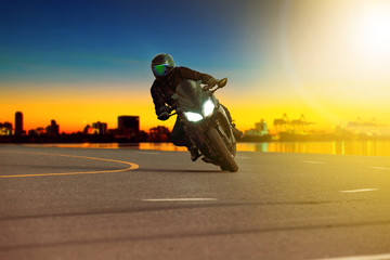 Naklejka premium man riding sport motorcycle leaning in sharp curve with traveling scene background