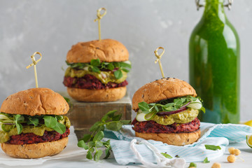 Vegan beet chickpea burgers with vegetables, guacamole and rye bun with green smoothie. Healthy vegan food concept.
