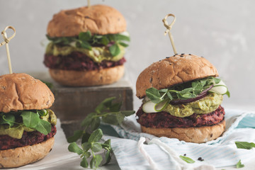 Vegan beet chickpea burgers with vegetables, guacamole and rye bun with green juice. Healthy vegan food concept.