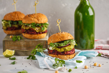 Vegan beet chickpea burgers with vegetables, guacamole and rye bun with green smoothie. Healthy vegan food concept.