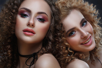 Fashion beauty portrait of two girls with afro curls and bright makeup.